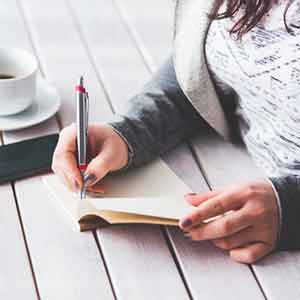 Photo of a woman writing on a book. Click on the photo for a list of best face scrubs. 